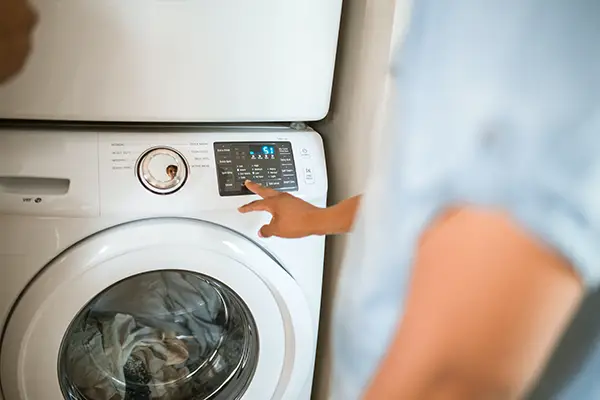 An appliance repair technician pointing at an error code on a washing machine